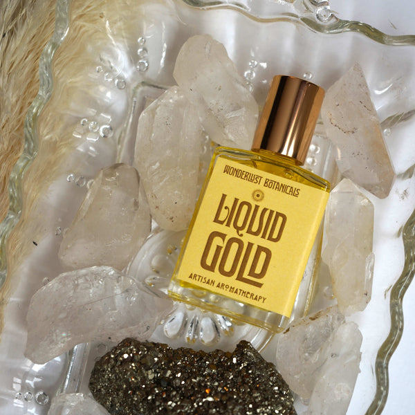 Wonderlust Botanicals Liquid Gold perfume oil, a warm and uplifting blend with lemongrass, orange, and cinnamon essential oils, in a 0.5 oz roll-on bottle.