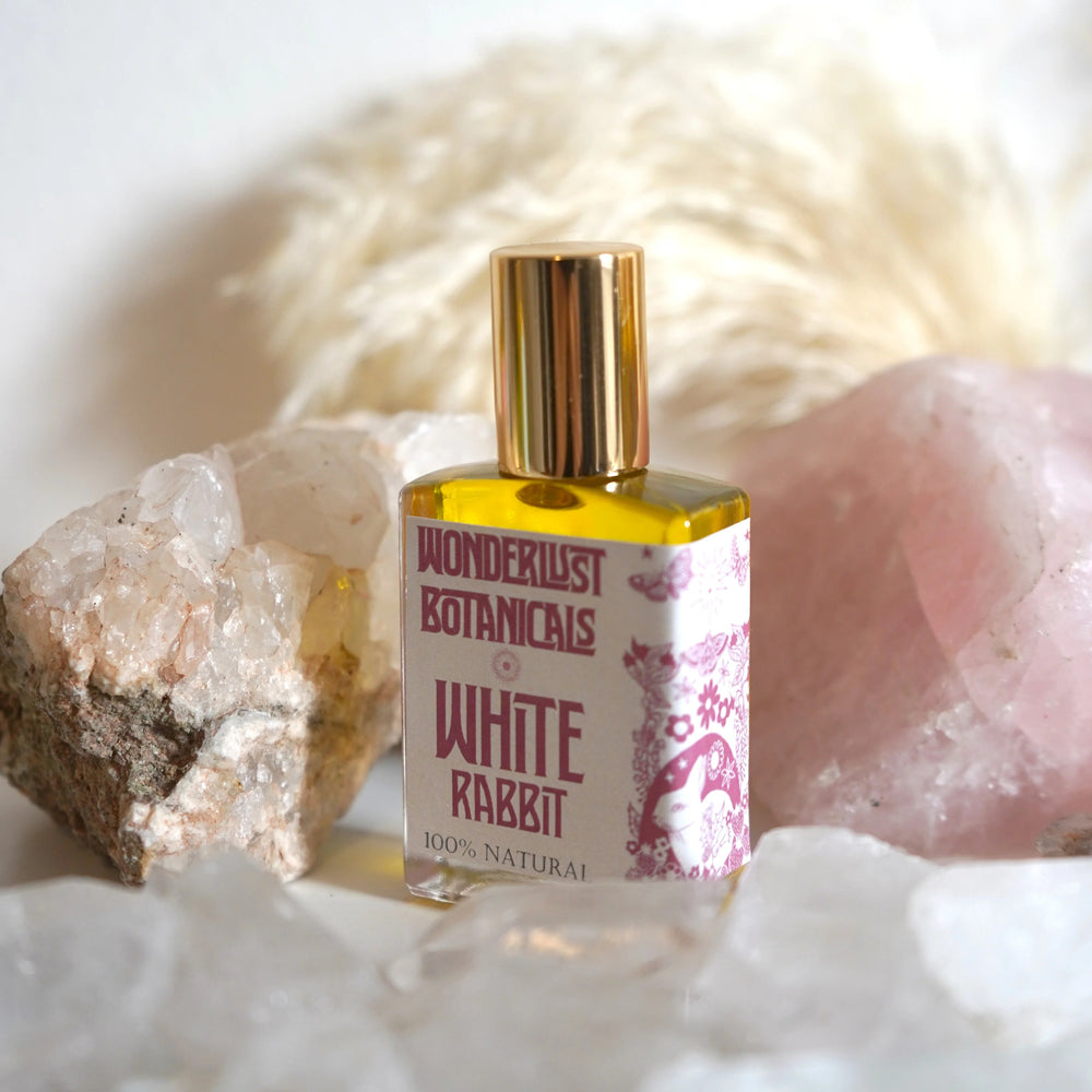 WONDERLUST BOTANICALS White Rabbit Aromatherapy Roll-On Perfume in a 0.5 oz glass bottle, featuring a fresh floral blend of patchouli, geranium, and bergamot essential oils.