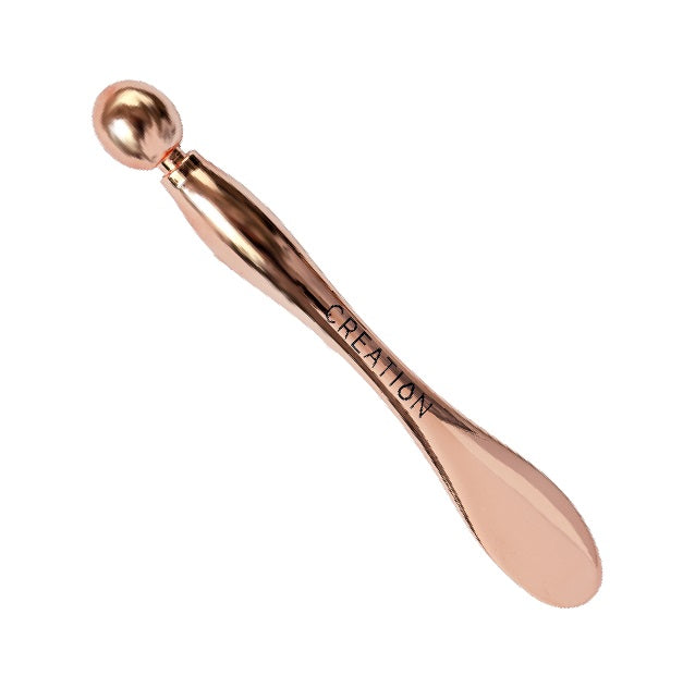 CREATION Rose Gold Eye Sculpting Multi-tool, a cosmetic and massage tool designed for applying eye cream, reducing puffiness, and relieving facial tension.