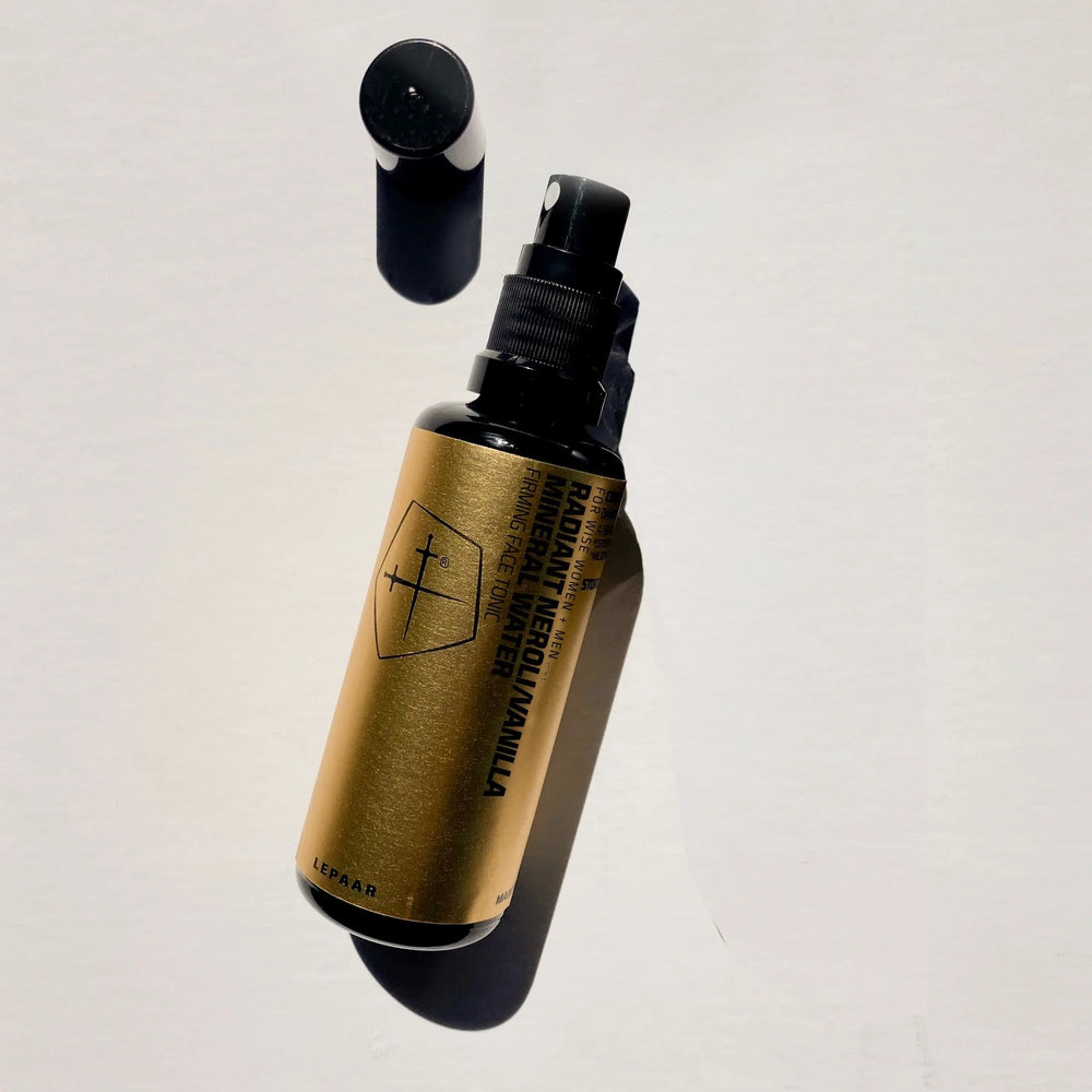 A 50ml amber glass spray bottle of LEPAAR Radiant Neroli/Vanilla Mineral Water, featuring a minimalist design with a geometric emblem and a black spray nozzle, set against a white background.